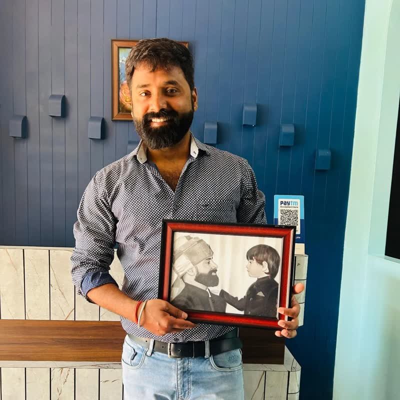 A customer holding a framed pencil portrait of an older man greeting a small child.