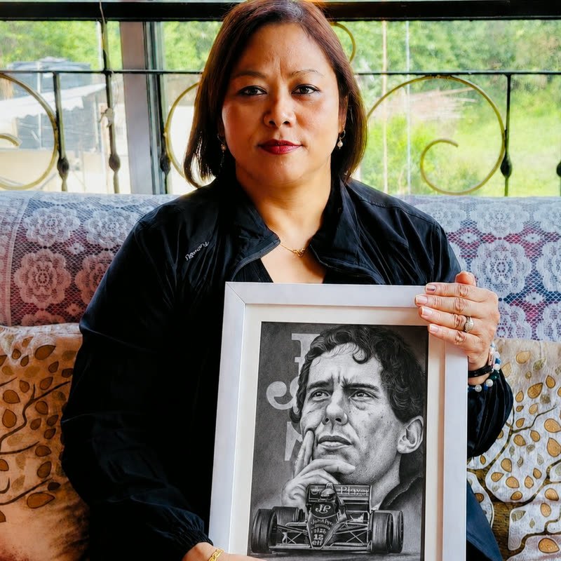 A customer holding a framed pencil portrait of a racing driver with his car, drawn from a photograph.